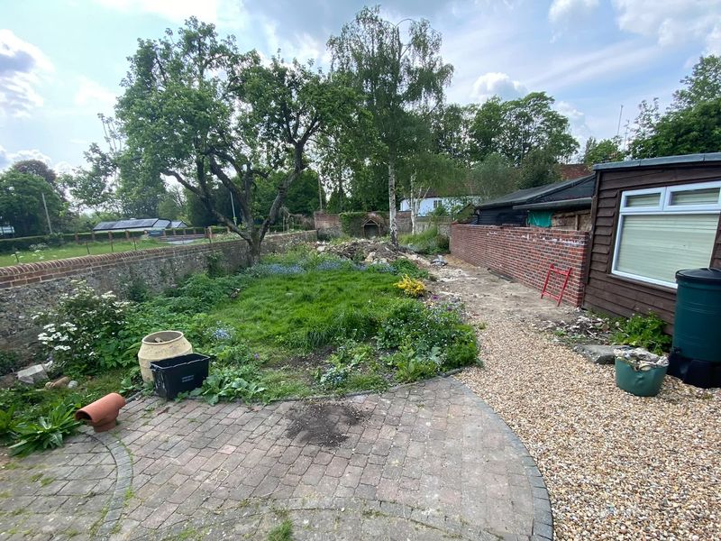 Before — the walled garden overgrown, weeds through the lawn and worn old block paving beside a gravel path