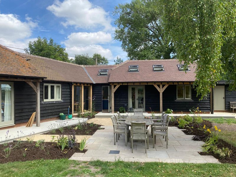 Barn conversion patio with dining set and established planting