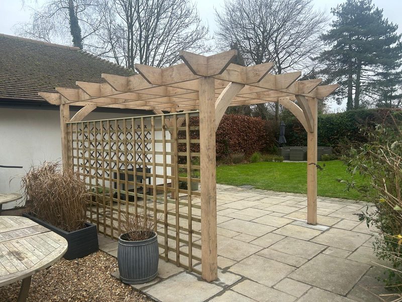 An oak pergola and trellis over a large sandstone patio built by Family Tree